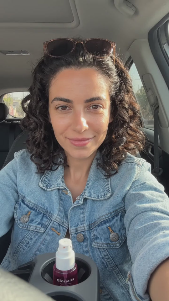 יוצרת תוכן מרססת את הבושם לשיער ברכב